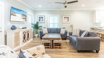 A living room with a sofa set, a coffee table, a dining table, and a kitchen area in the background.