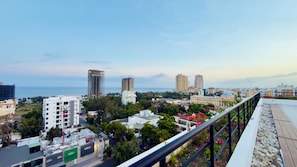 Stadtansicht mit Wolkenkratzern, Blick auf das Meer und ein Balkon mit Geländer.