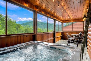 Ein Whirlpoolbereich mit Bergblick, Holzwänden und Lichterketten.
