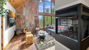 Ein rustikales Interieur mit Holzbalkendecke, Kamin und großem Fenster.