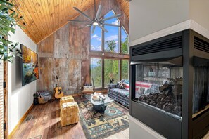 Ein rustikales Interieur mit Holzbalkendecke, Kamin und großem Fenster.