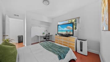 A bedroom with a bed, a TV, a dresser, and a heater.