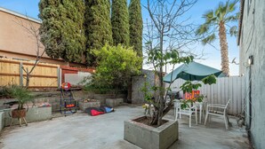 A backyard with a concrete patio, a small tree, a white chair, and a blue playset. - Garage, Gated Yard, near SD Gaslamp, DT, 4BR/2Bth (National City)