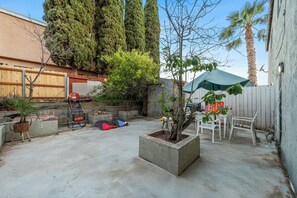 A backyard with a concrete patio, a small tree, a white chair, and a blue playset. - Garage, Gated Yard, near SD Gaslamp, DT, 4BR/2Bth (National City)