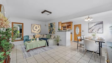 Ein geräumiges Wohnzimmer mit Essbereich, einer Küche und einem großen Spiegel.