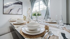 A dining table set with white plates, bowls, and cutlery, with a vase of white flowers and a decorative sculpture. - Garage, Gated Yard, near SD Gaslamp, DT, 4BR/2Bth (National City)