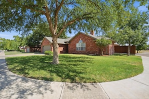 A single-story brick house with a front yard, a garage, and a driveway. - Tranquil Retreat - 3BR/3BA - Centrally Located (Lubbock)