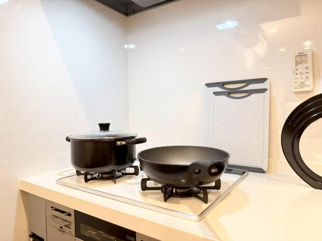 A kitchen with a stove, a pot, and a frying pan on a countertop.