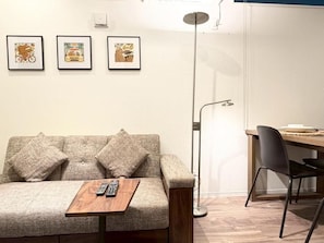 A modern living room with a sofa, a coffee table, a dining table with chairs, and framed artwork on the wall. - NIKYO Taisho BLA Private Villa OSAKA (Osaka)
