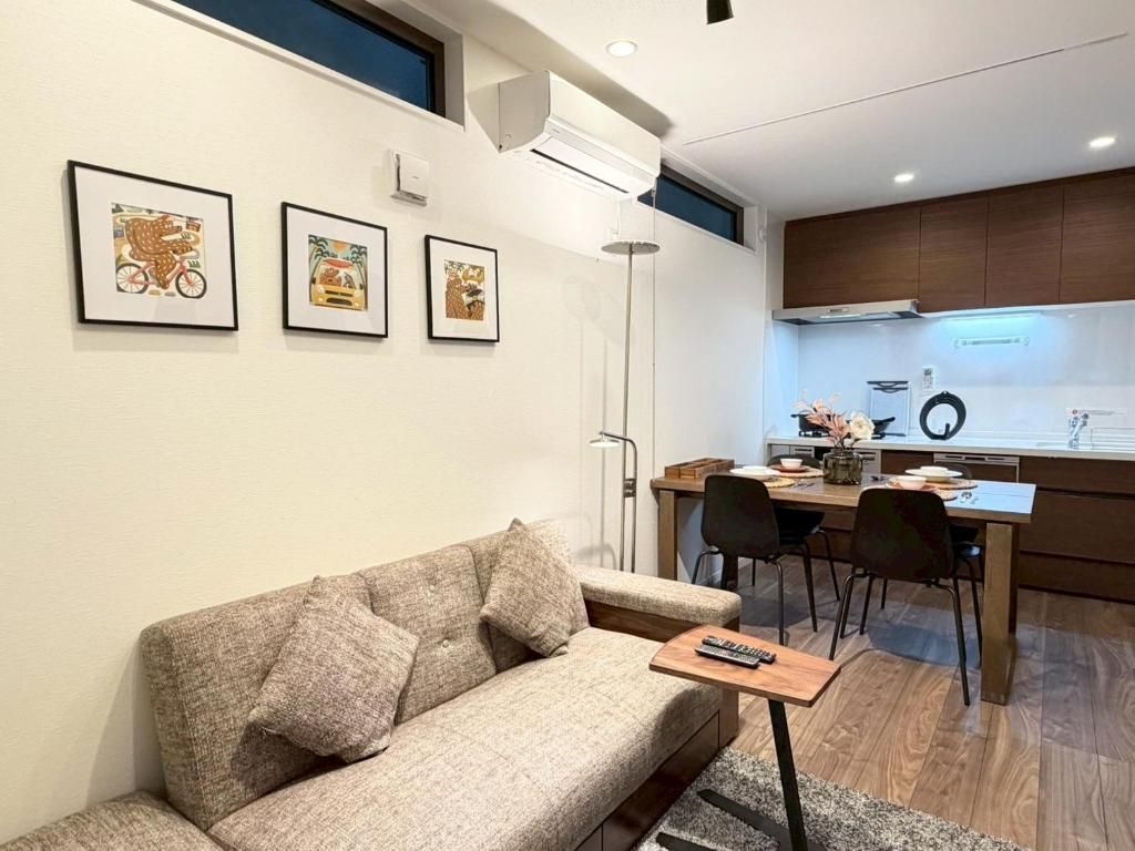 A modern living room with a sofa, a coffee table, and a dining area with chairs and a table.