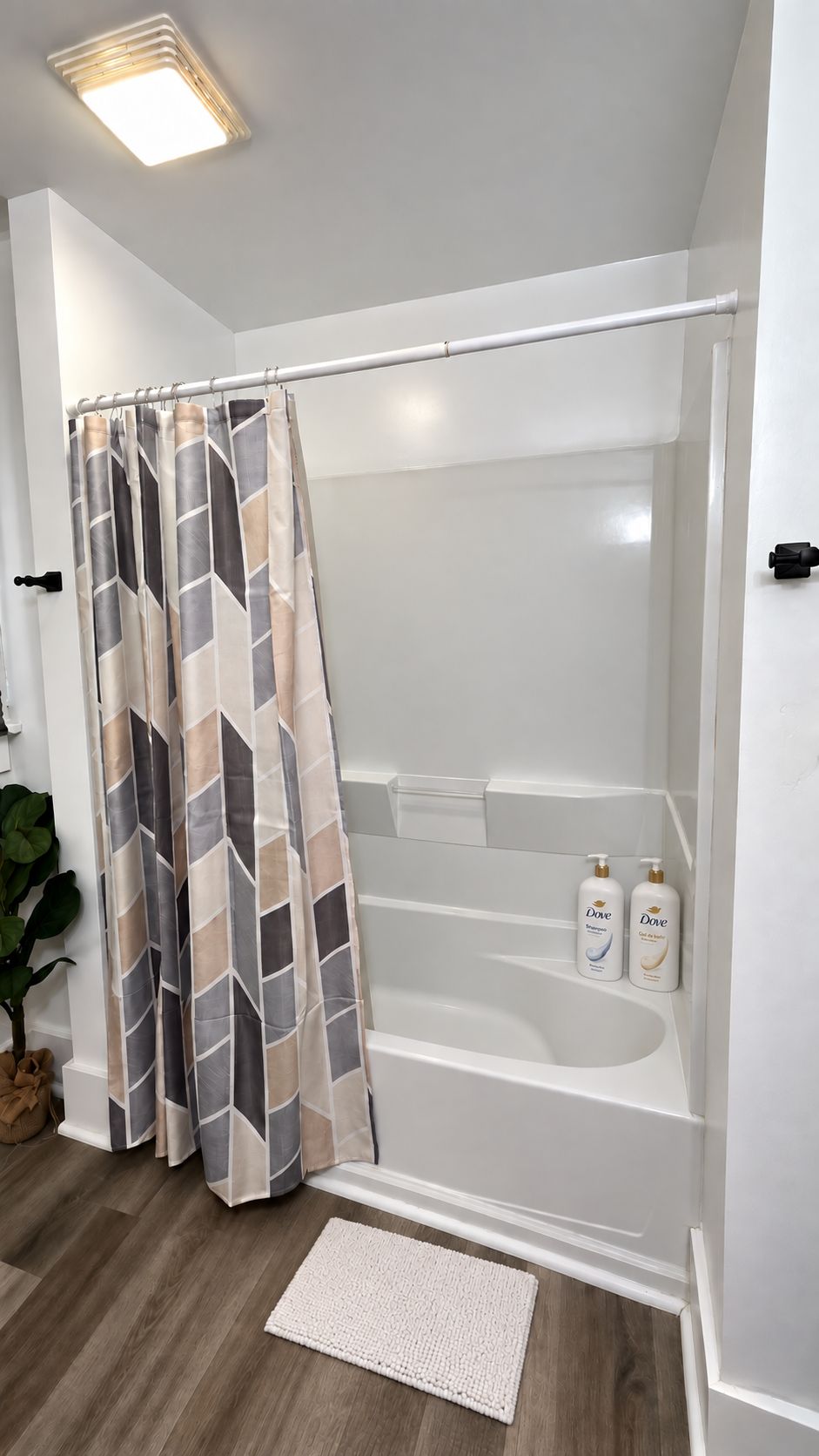 Une salle de bain avec un rideau de douche, une baignoire et deux bouteilles de shampoing Dove.