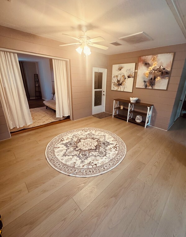 A spacious room with a large round carpet, a ceiling fan, and artwork on the walls. - Home Sweet Home in Sun City Center/Ruskin area (Sun City Center)