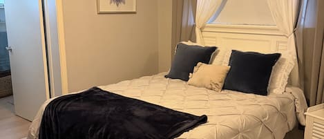 A bedroom with a bed, a ceiling fan, a window with curtains, and a rug.
