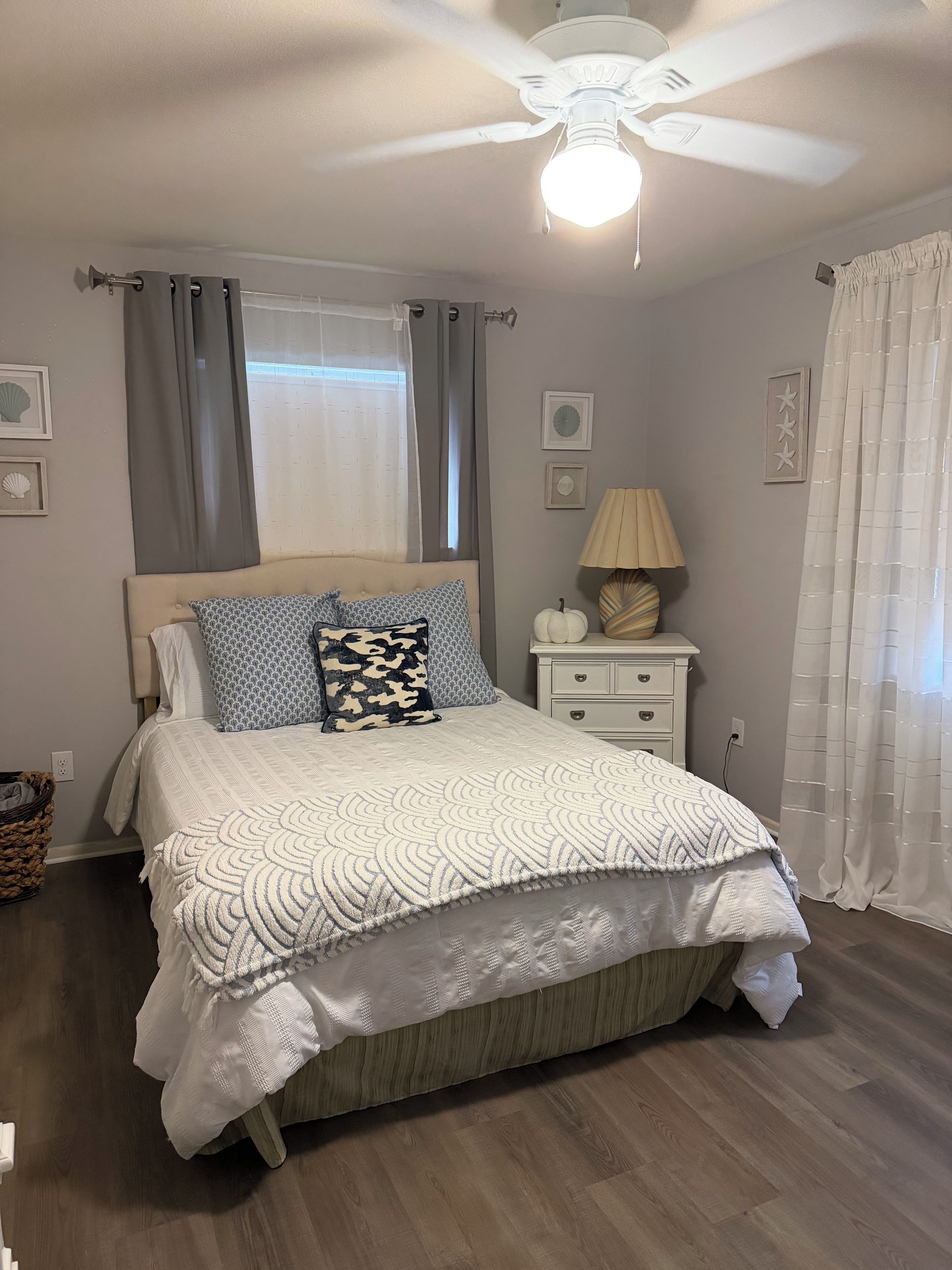 Ein Schlafzimmer mit einem Bett, einem Nachttisch, einer Lampe und einem Deckenventilator.