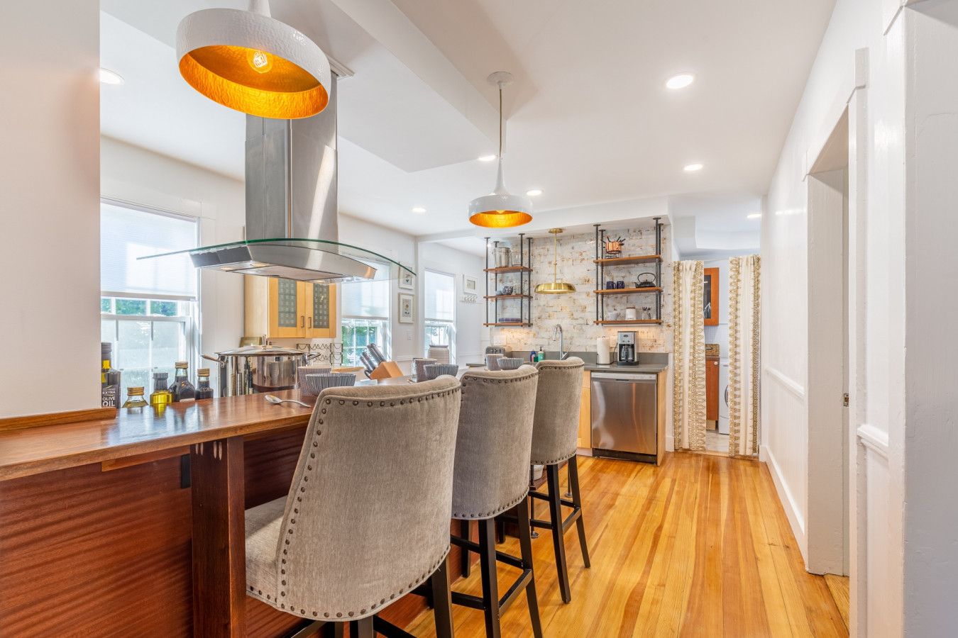 Una cocina moderna con barra, suelo de madera e iluminación colgante.