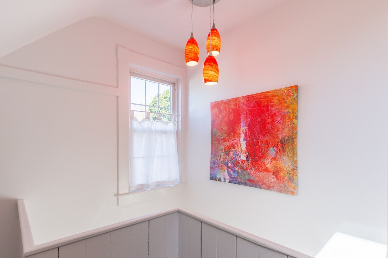 A room with a window, a painting, and a staircase.