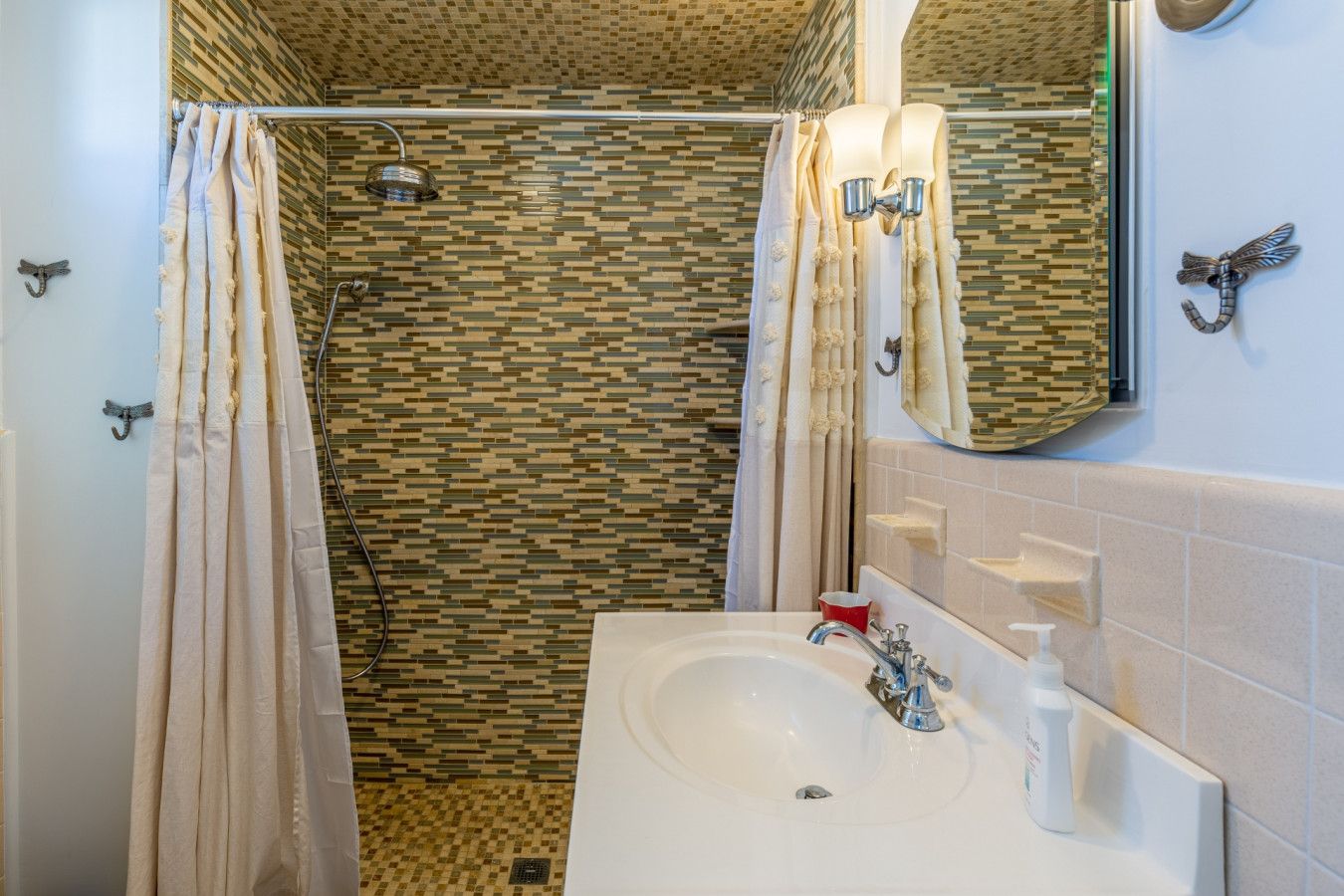 Un baño con ducha, lavamanos y espejo.