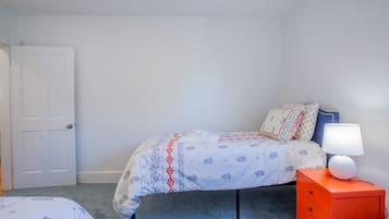 A bedroom with a bed, a nightstand, a lamp, and a door.