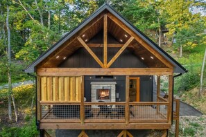 A cabin with a fireplace, wooden deck, and a fenced-in area.