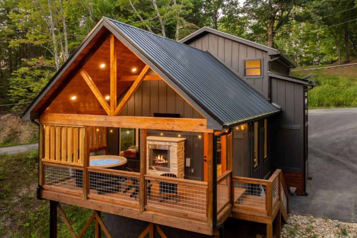 A wooden cabin with a fireplace, a hot tub, and a deck.