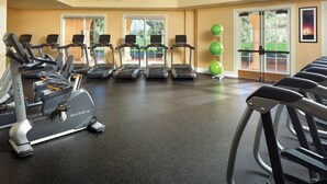 Ein Fitnessraum mit Laufbändern, Crosstrainern und grünen Trainingsbällen.