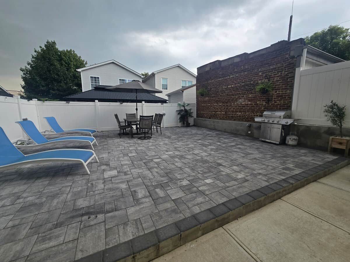 A patio area with a brick floor, outdoor furniture, and a barbecue grill.
