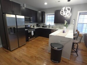 A modern kitchen with dark cabinets, stainless steel appliances, and a central island.