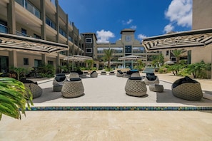 Une cour d’hôtel avec des espaces de repos en plein air, une piscine et un bâtiment doté d’un clocher.