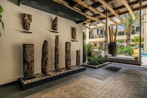 A lobby with a modern design, featuring a series of wooden sculptures on display and a seating area with a swing chair. - New Ground Floor 1BR Condo ~ Close to Eagle Beach (Noord)