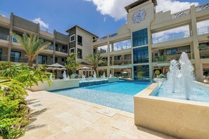 A hotel with a swimming pool, palm trees, and a fountain. - New Ground Floor 1BR Condo ~ Close to Eagle Beach (Noord)