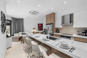 A modern kitchen with a central island, stainless steel appliances, and a dining area with bar stools. - New Ground Floor 1BR Condo ~ Close to Eagle Beach (Noord)