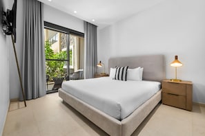Une chambre d’hôtel moderne avec un grand lit, deux lampes de chevet, une table de chevet en bois et une vue sur la verdure.
