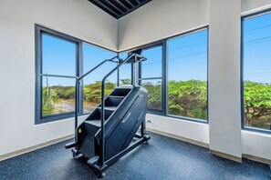 A gym with a stationary bike, large windows, and a view of greenery. - New Ground Floor 1BR Condo ~ Close to Eagle Beach (Noord)