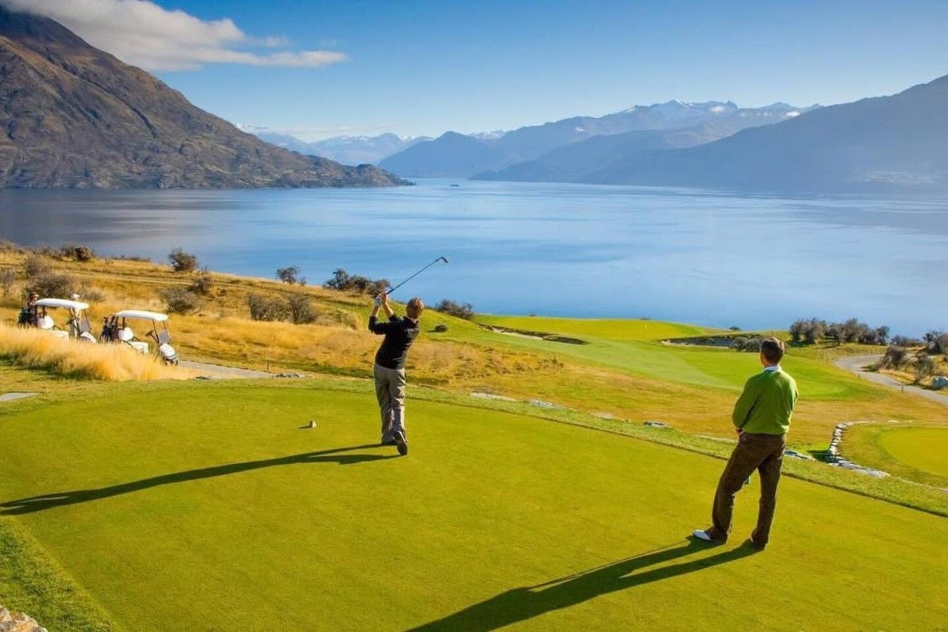A golf course with a view of a lake and mountains in the background.
