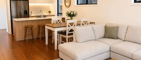 A modern living room with a sofa, a coffee table, and a dining area with chairs and a table.