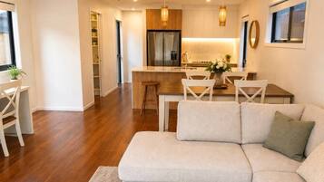 Una sala moderna con un sofá, una mesa de comedor y una cocina al fondo.