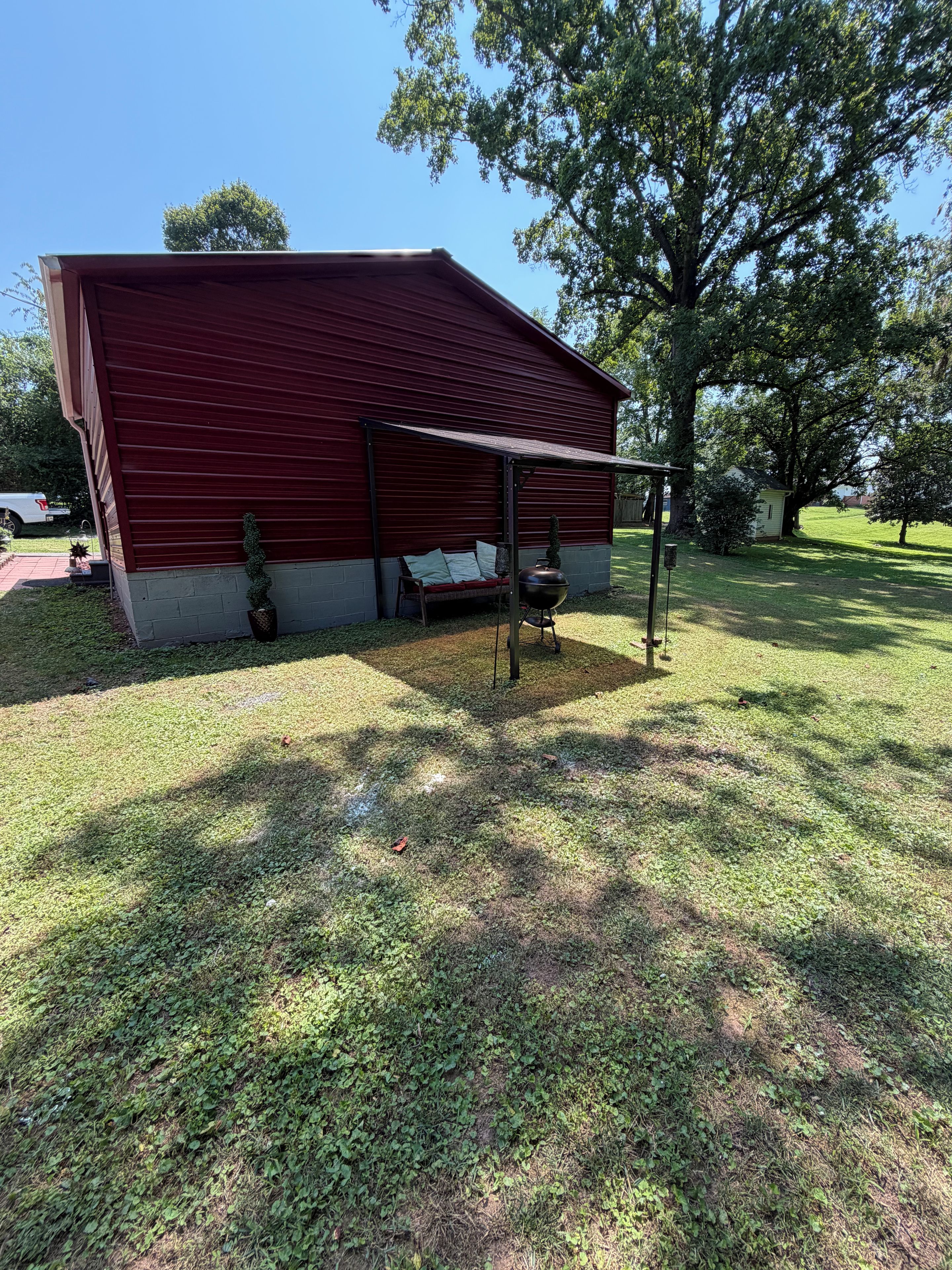 Un bâtiment rouge doté d’un espace de repos abrité et d’un barbecue.
