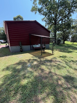 A red building with a covered seating area and a barbecue grill.