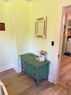 A teal dresser with drawers, a mirror, and a vase with flowers.