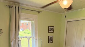 Una camera da letto con un letto, una finestra, una porta e una ventola a soffitto.