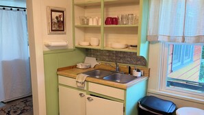 Una cucina compatta con lavello, mobili e una finestra.