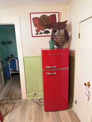 A red refrigerator with a note on the door, a framed picture on the wall, and a blue chair in the background. - Fantastic 3-bedroom dog friendly retro farmhouse in charming Jonesville (Jonesville)
