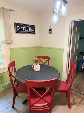 A dining area with a round table and red chairs, a coffee bar sign on the wall, and a window with curtains. - Fantastic 3-bedroom dog friendly retro farmhouse in charming Jonesville (Jonesville)