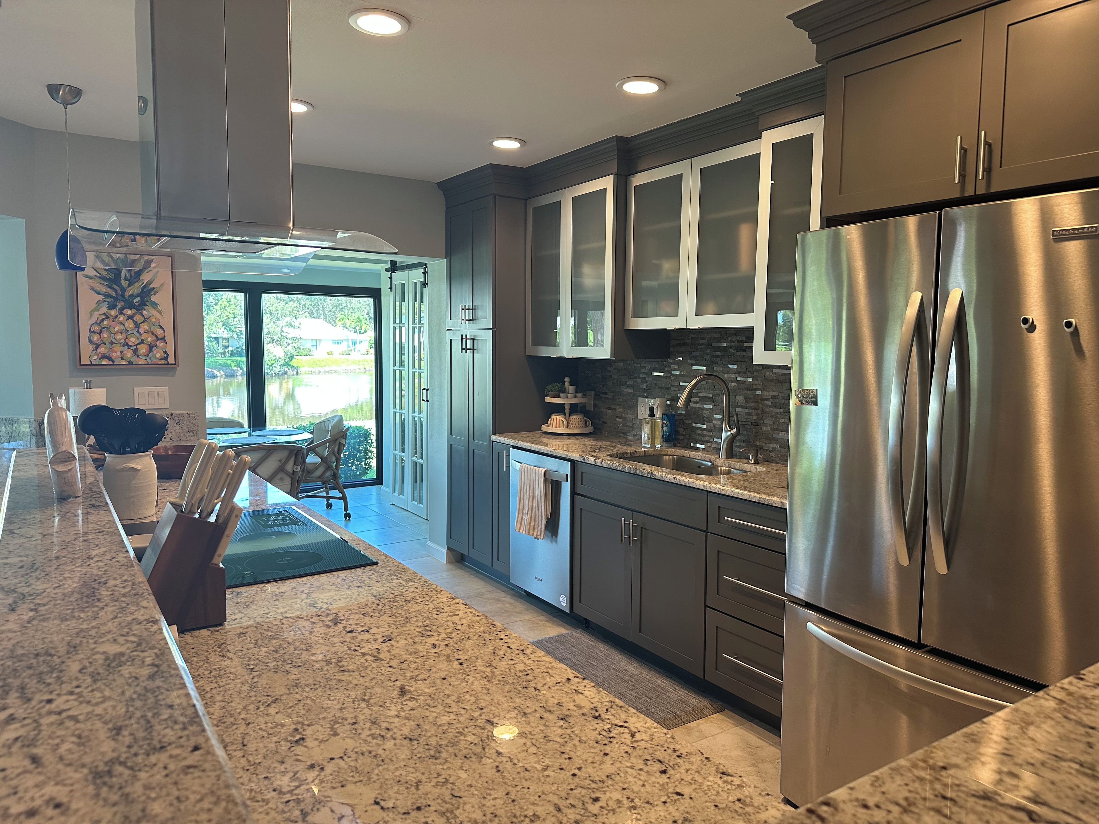 A modern kitchen with stainless steel appliances, granite countertops, and a view to the outside.