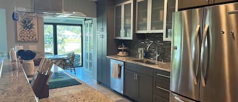 A modern kitchen with stainless steel appliances, granite countertops, and a view to the outside.
