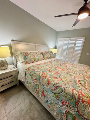 A bedroom with a bed, nightstands, a ceiling fan, and a window with blinds. - Serene 2 Bedroom 2 Bath Villa with Lakeview in Myrtle Trace (Venice)
