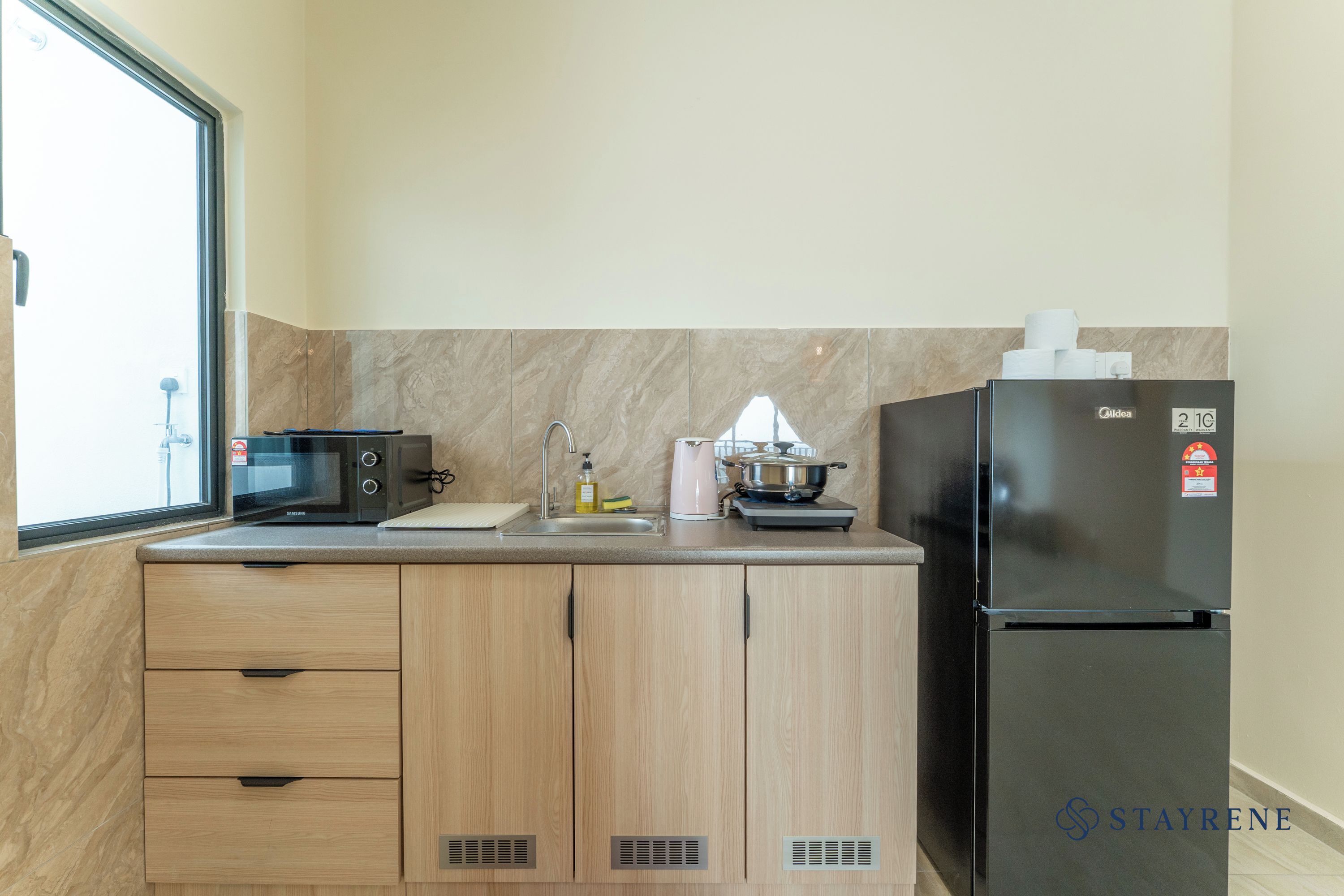 A compact kitchen with a microwave, sink, and a refrigerator.