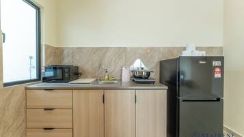 A compact kitchen with a microwave, sink, and a refrigerator.