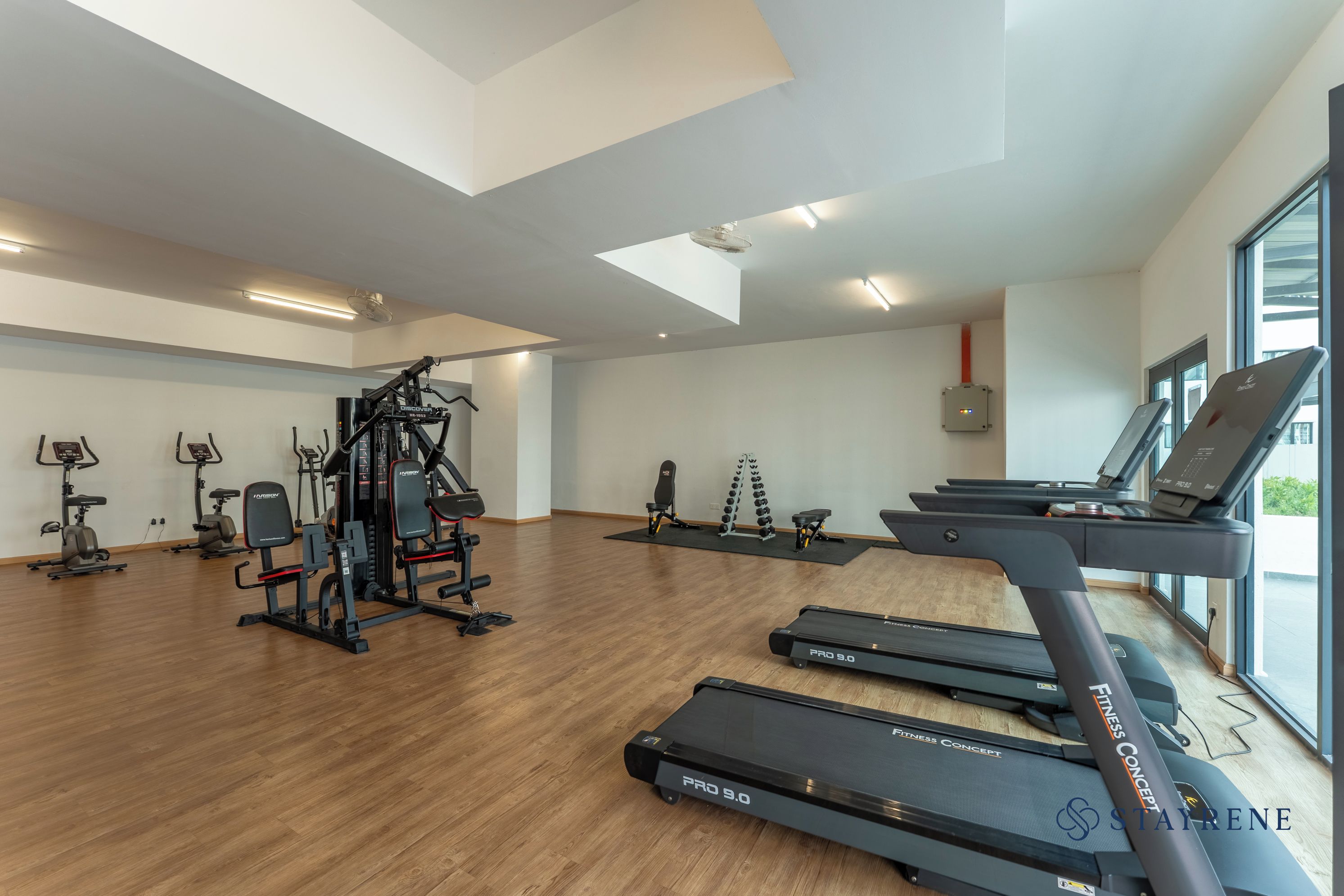 A gym with treadmills, weight machines, and a large window.