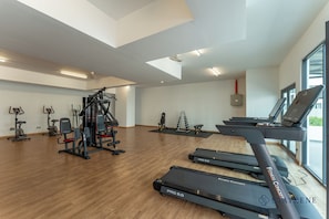 A gym with treadmills, weight machines, and a large window. - Ambience Residence by Stayrene (Melaka)